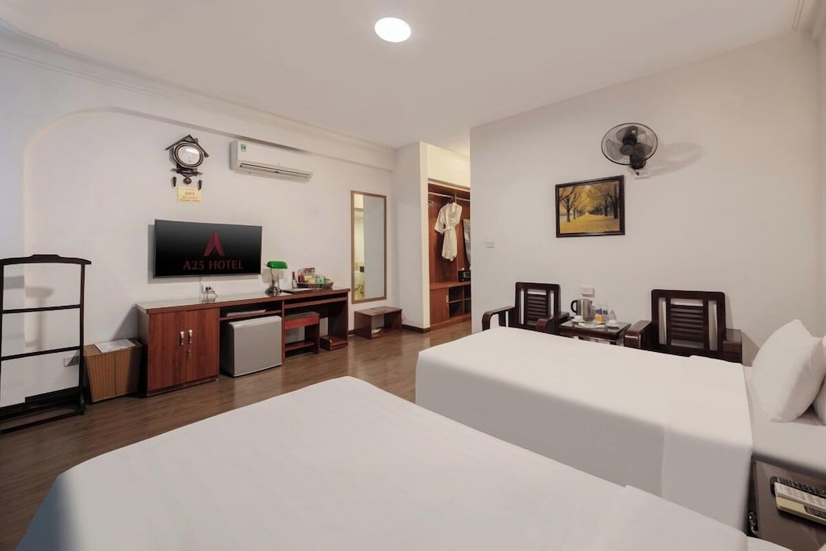 Habitación de hotel con cama, escritorio, armario, televisión y un cuadro en la pared.