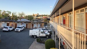 Un motel con estacionamiento, varias habitaciones y un camión de reparto John Holland estacionado afuera.