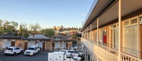 A motel with a parking lot, several rooms, and a John Holland delivery truck parked outside.