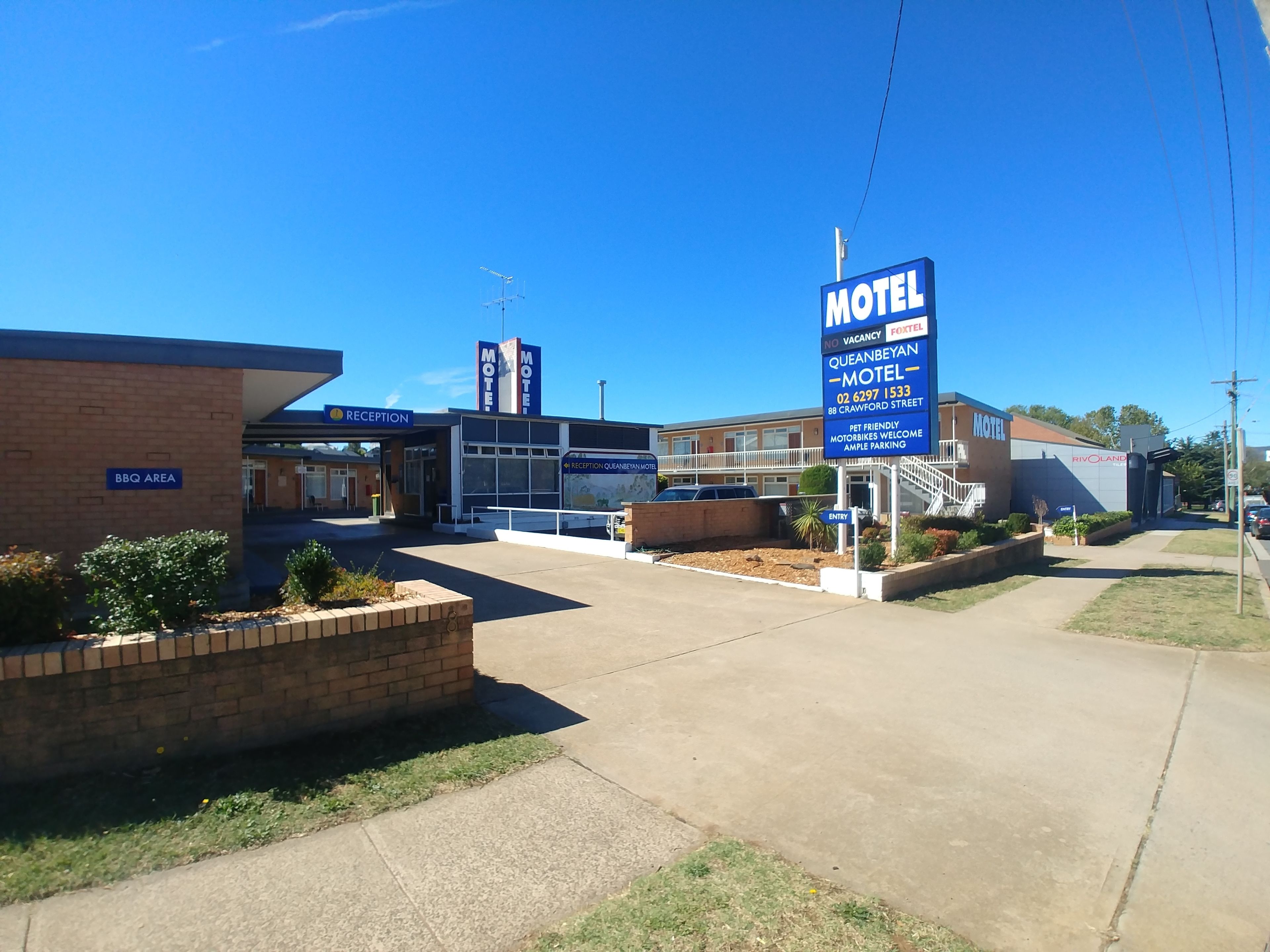 A motel with a reception area, BBQ area, and a sign indicating no vacancy.