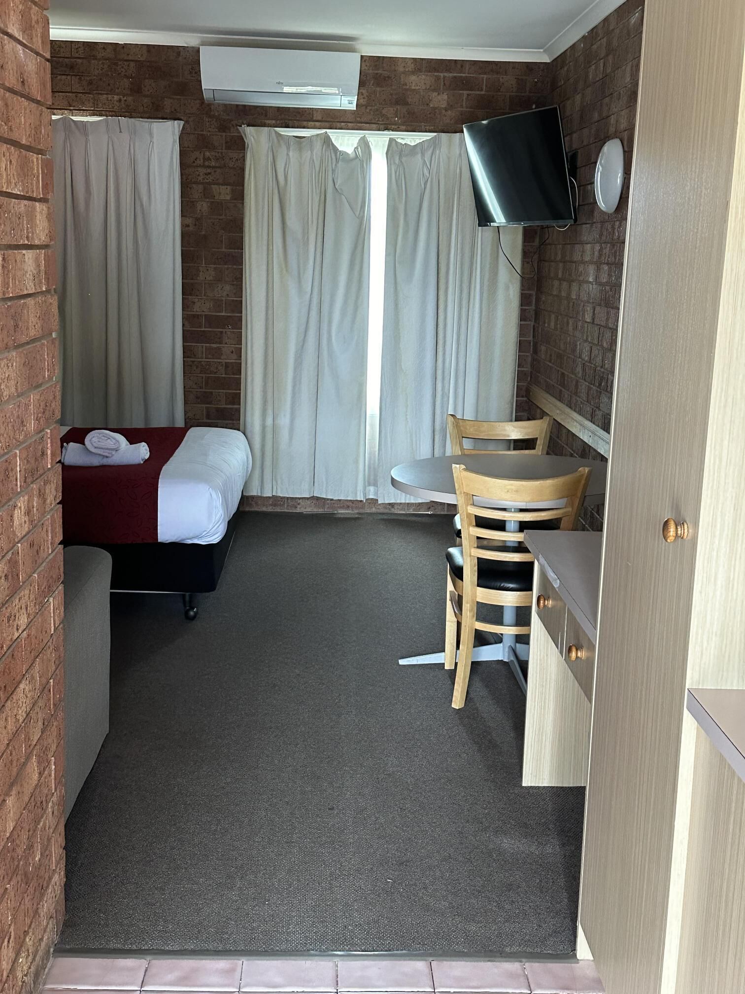 A compact hotel room with a bed, a desk, and a TV.