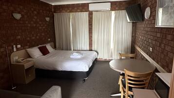 Une chambre d’hôtel équipée d’un lit, d’un bureau, d’une chaise, d’un canapé et d’une télévision.