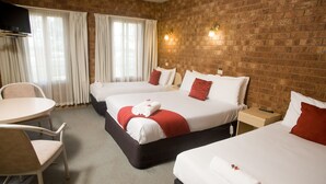 A hotel room with two beds, a TV, a table, and a chair.
