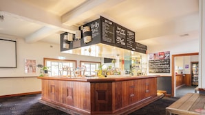 A bar area with a wooden counter, a chalkboard menu, and a patterned carpet. - The Civic Hotel (Inglewood)