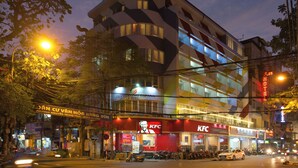 A multi-story building with a KFC restaurant on the ground floor, a hotel sign above, and several parked vehicles in front.