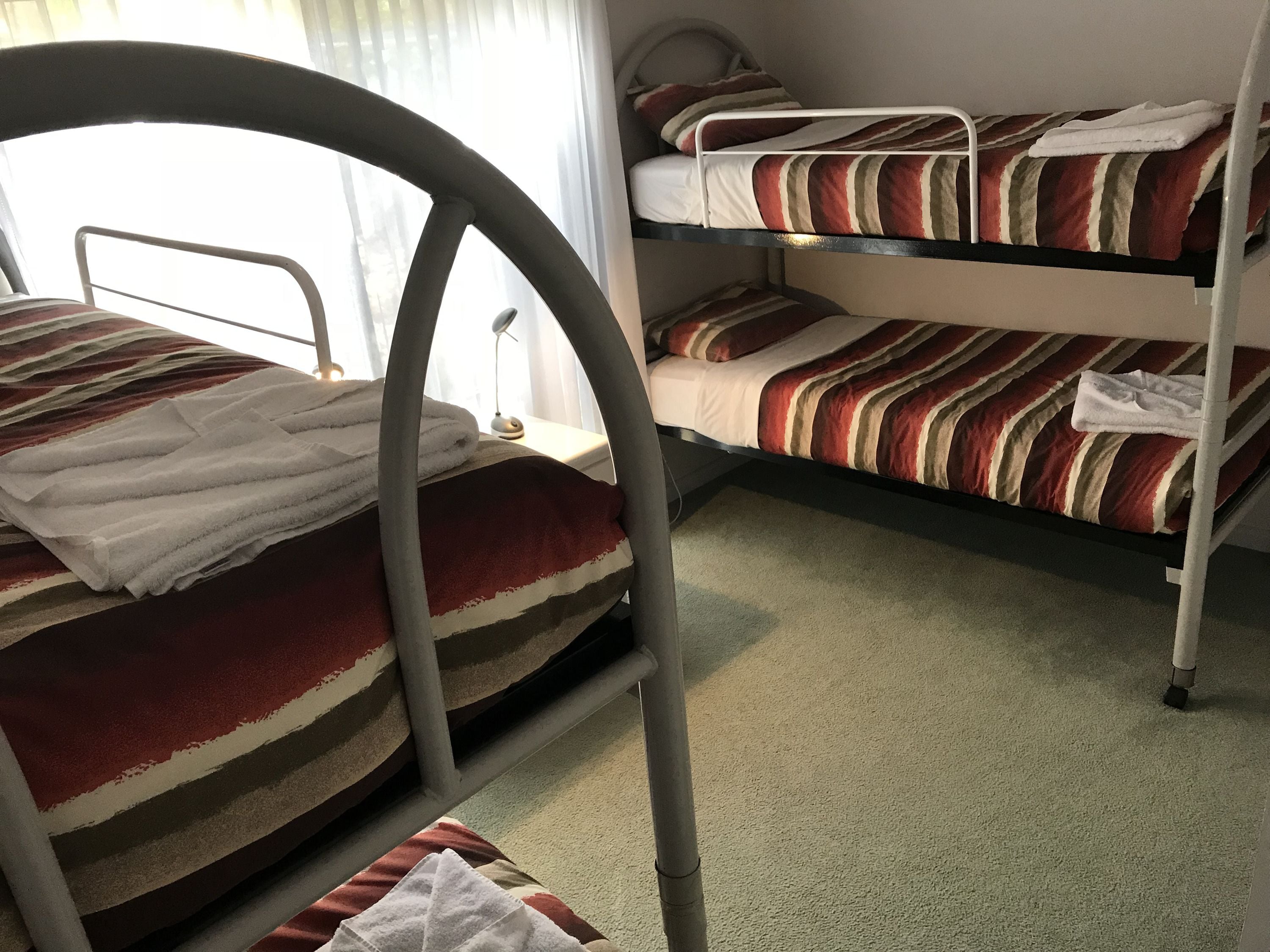 A bunk bed room with striped bedding and a metal ladder.