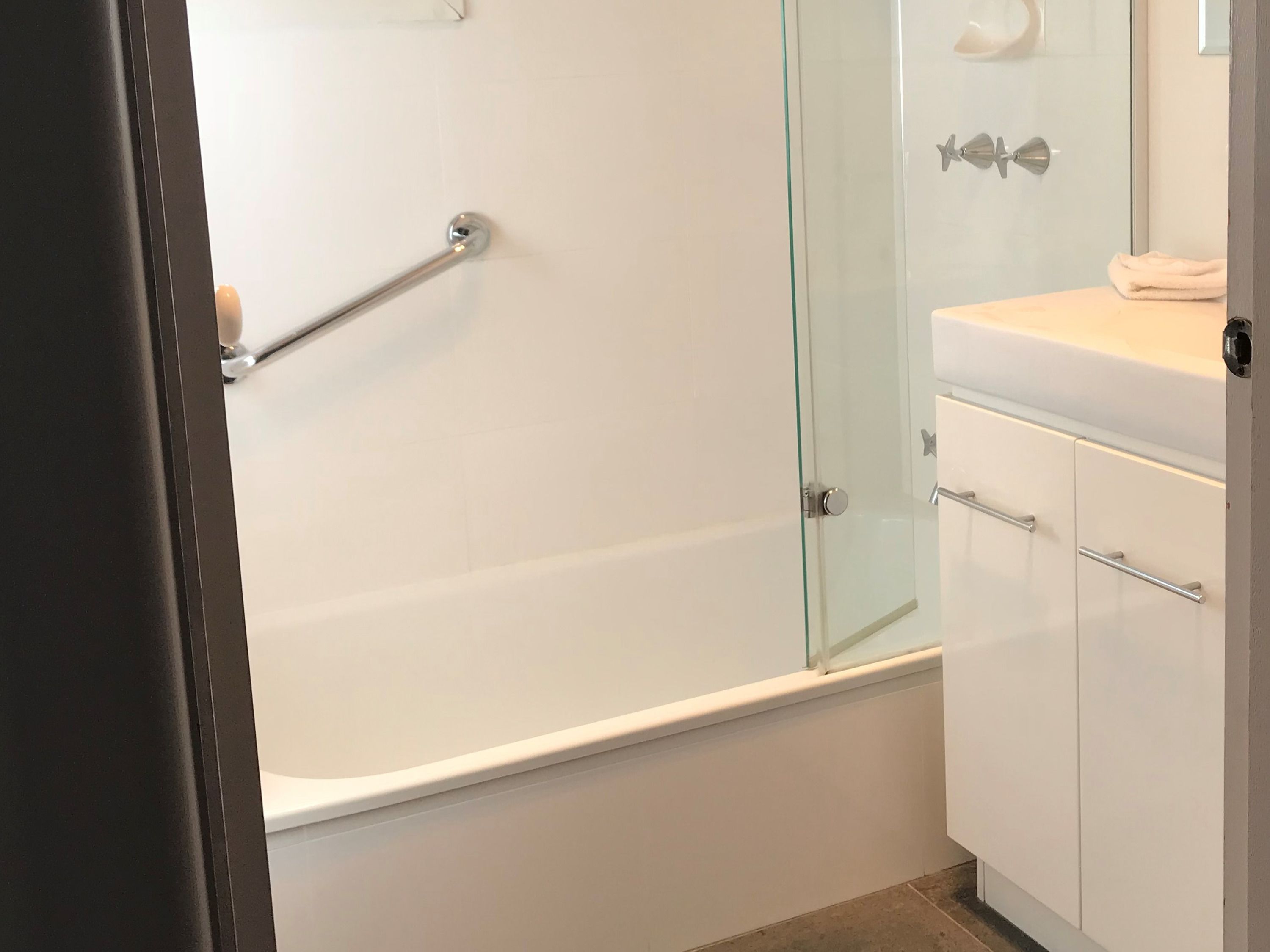 Une salle de bain moderne avec une douche à parois de verre, une baignoire blanche et un meuble-lavabo avec un miroir.
