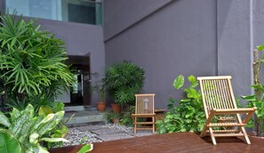 A wooden deck with two wooden chairs, surrounded by potted plants and a small garden area. - Marvelux Hotel (Malacca City)