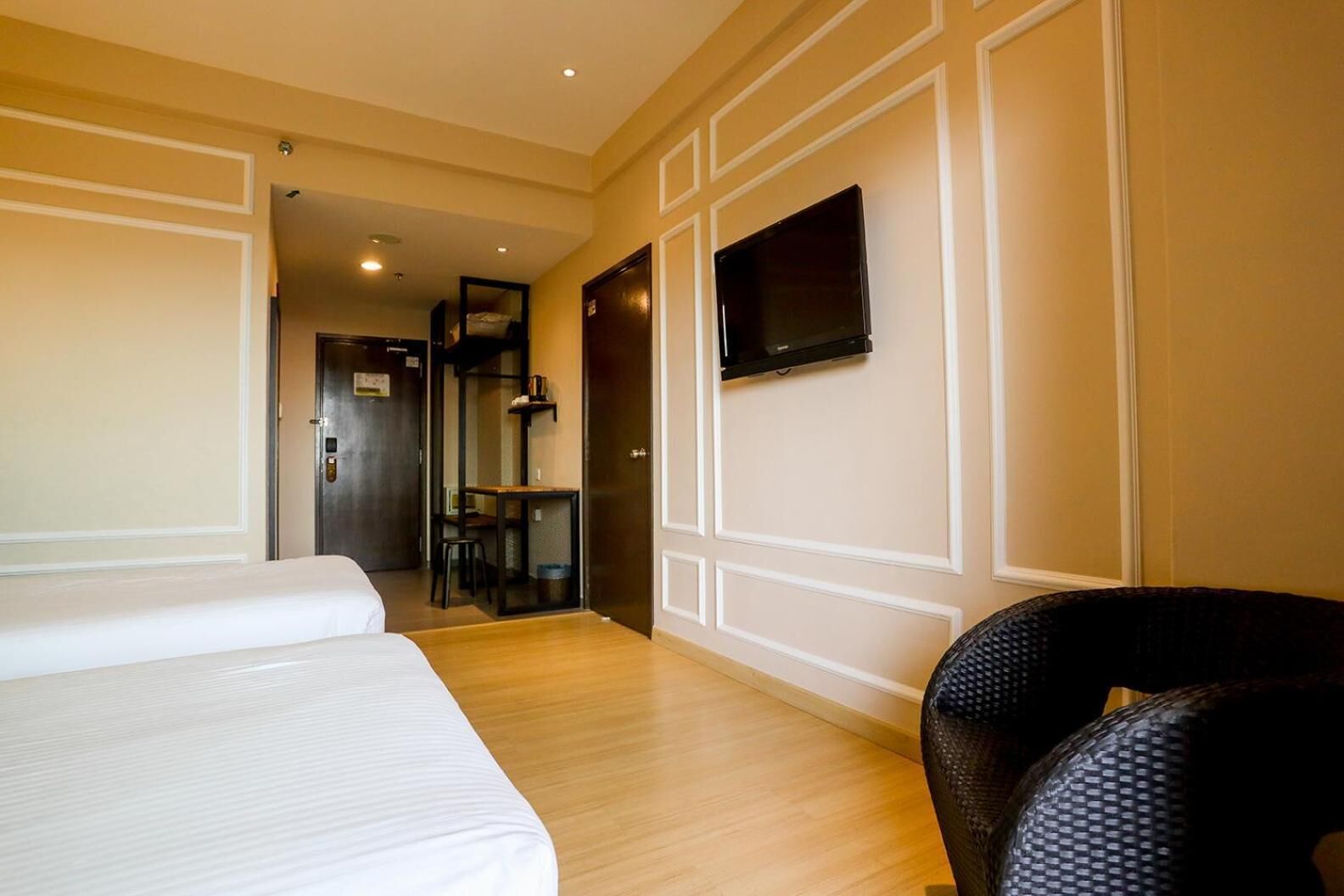 Une chambre d’hôtel avec deux lits, un téléviseur fixé au mur et une petite table avec une chaise.