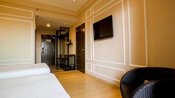 Une chambre d’hôtel avec deux lits, un téléviseur fixé au mur et une petite table avec une chaise.