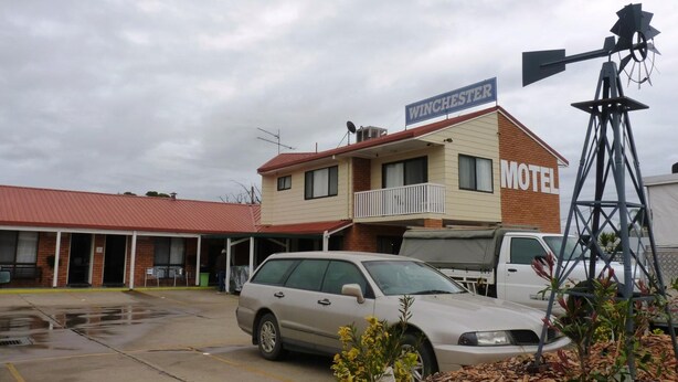 A motel with a red roof, a sign reading "WINCHESTER," and a white van parked in front.