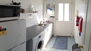Une cuisine compacte équipée d’un four à micro-ondes, d’un évier et d’un lave-linge.