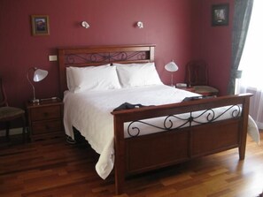 A bedroom with a wooden bed, two bedside tables, a chair, and a nightstand.
