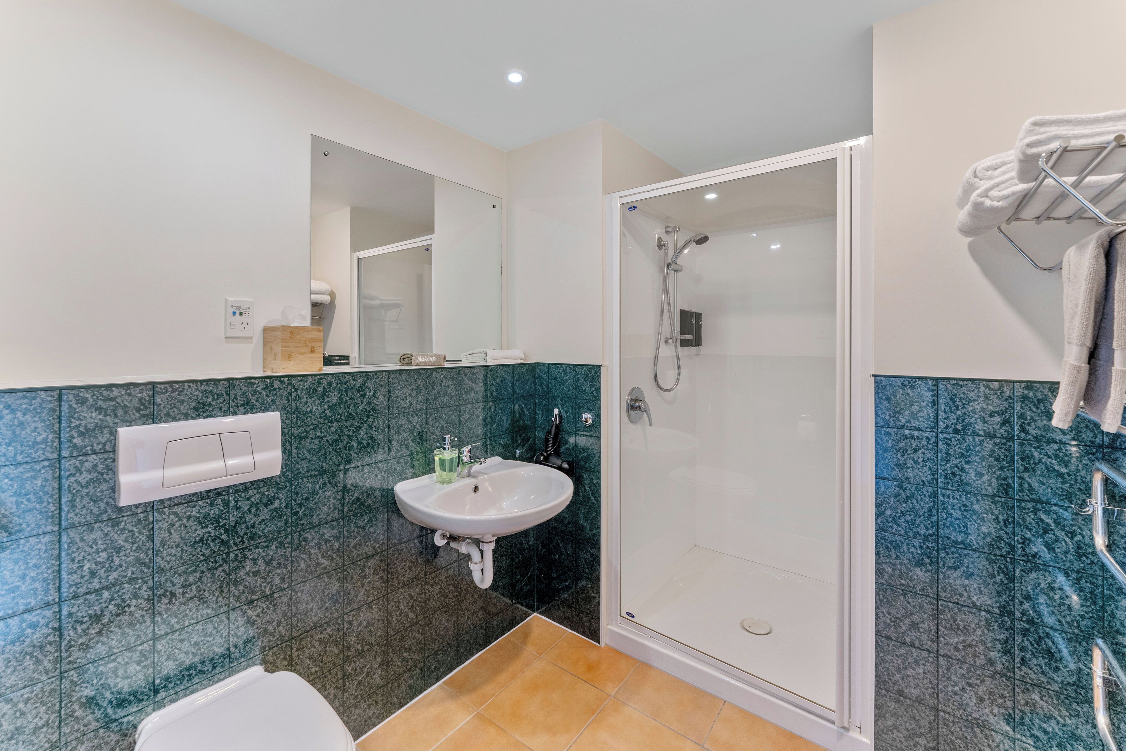 Une salle de bain moderne avec une douche à parois de verre, un lavabo blanc et des toilettes.