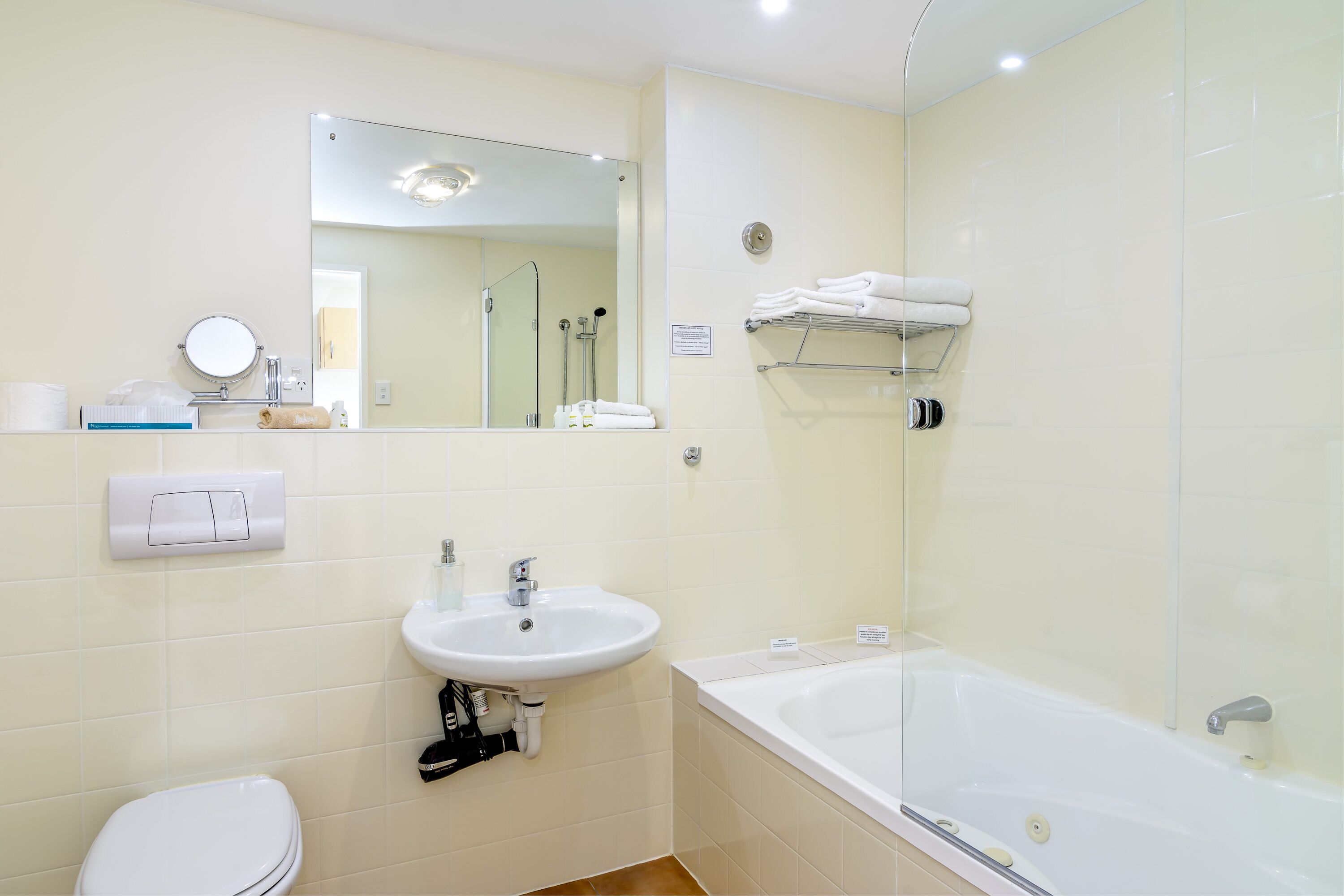 A bathroom with a toilet, sink, mirror, and bathtub.