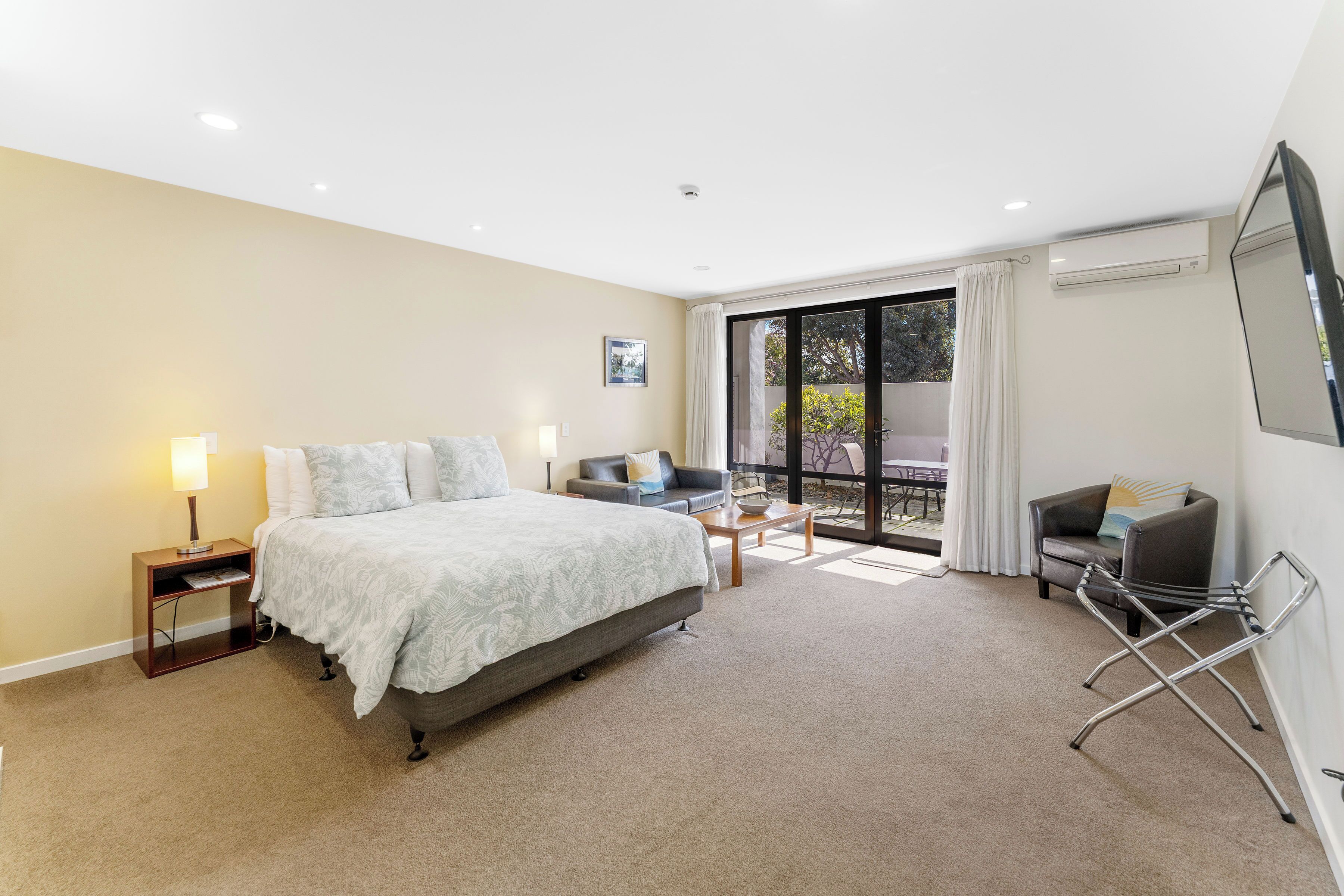 Una habitación de hotel moderna con una cama grande, un sofá, una mesita y una silla.