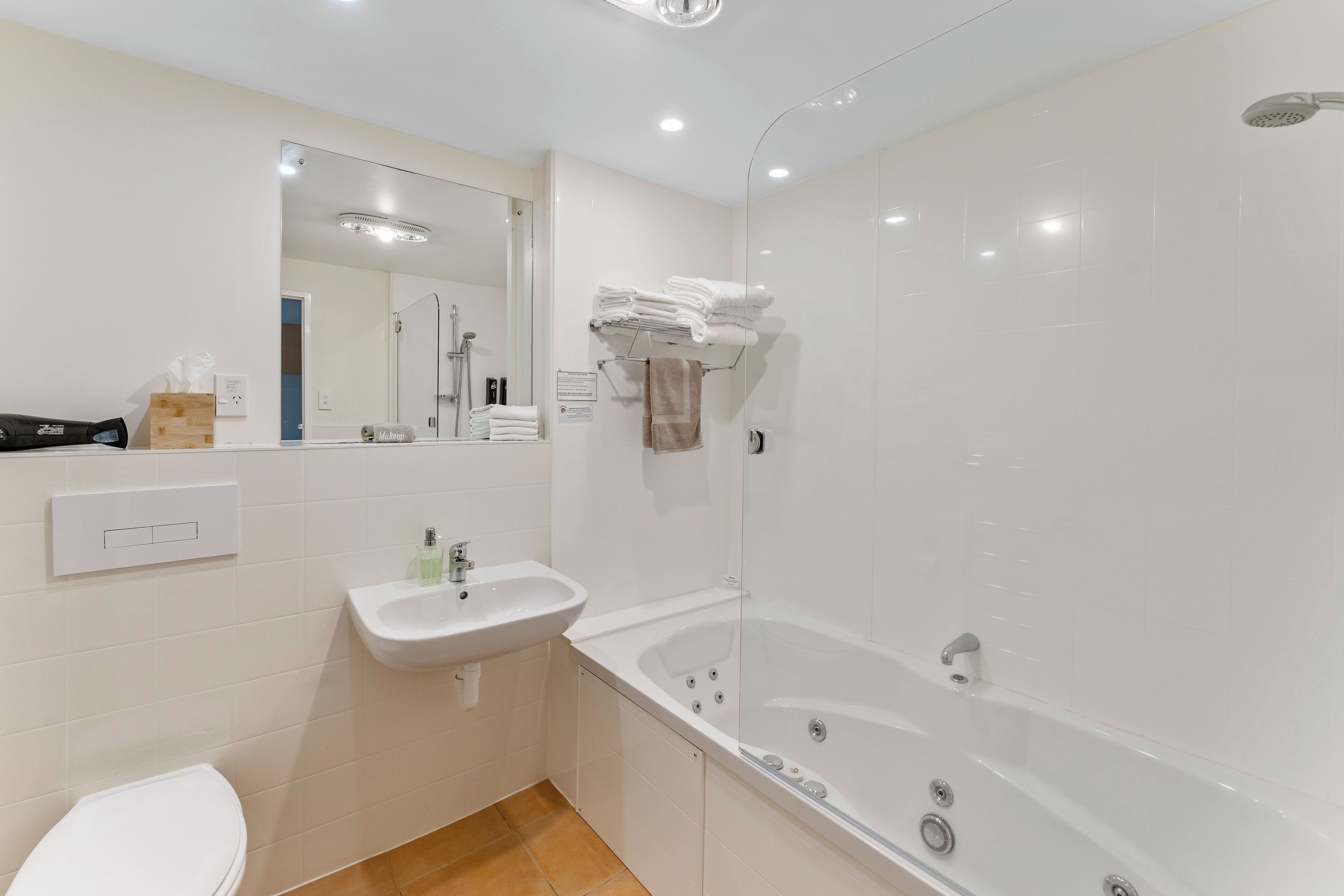A modern bathroom with a white sink, a toilet, a glass-enclosed shower, and a large bathtub.
