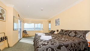 Habitación de hotel con una cama grande, una silla, un escritorio y vistas al mar.