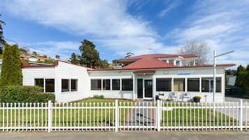 A two-story building with a red roof, white exterior, and a white picket fence.