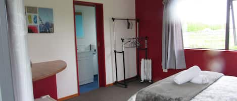 Ein Schlafzimmer mit Bett, einem kleinen Schreibtisch, einer Heizung und einem Fenster mit Vorhängen.