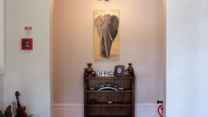 Un passadís amb una taula de fusta de consula amb la inscripció “OFICINA” i un quadre d'un elefant penjat a la paret.