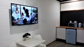 A modern kitchen with white cabinetry, a built-in microwave, and a small refrigerator. - Kurri Motor Inn (Kurri Kurri)