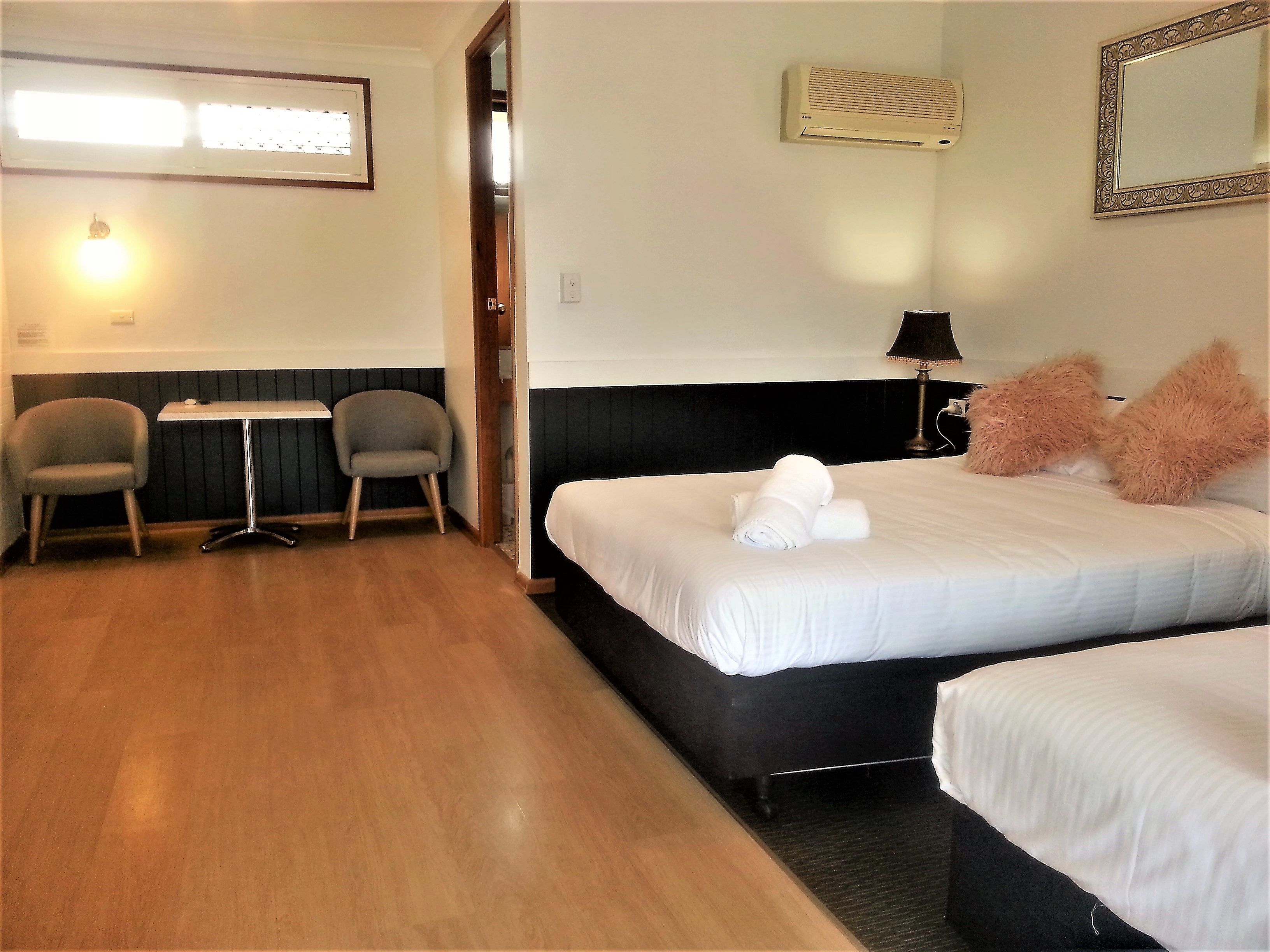 Une chambre d’hôtel avec deux lits, un bureau, deux chaises, une lampe et un miroir.