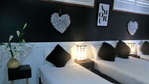 A hotel room with two beds, white linens, black pillows, a vase with flowers, and heart-shaped wall decorations. - Kurri Motor Inn (Kurri Kurri)