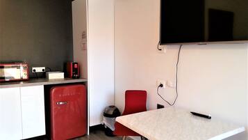 A compact kitchen with a microwave, coffee maker, and a red refrigerator.
