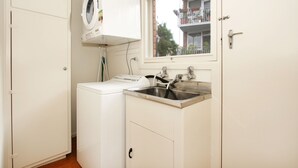A laundry room with a washing machine, a sink, and a window overlooking a balcony. - Lisson Holiday Rental (Hawthorn)