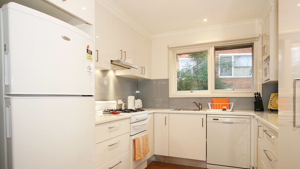 A modern kitchen with white cabinetry, a built-in oven, a dishwasher, and a window providing natural light. - Lisson Holiday Rental (Hawthorn)