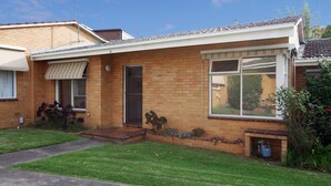 A single-story brick house with a front porch, a window with a view, and a small garden area. - Lisson Holiday Rental (Hawthorn)