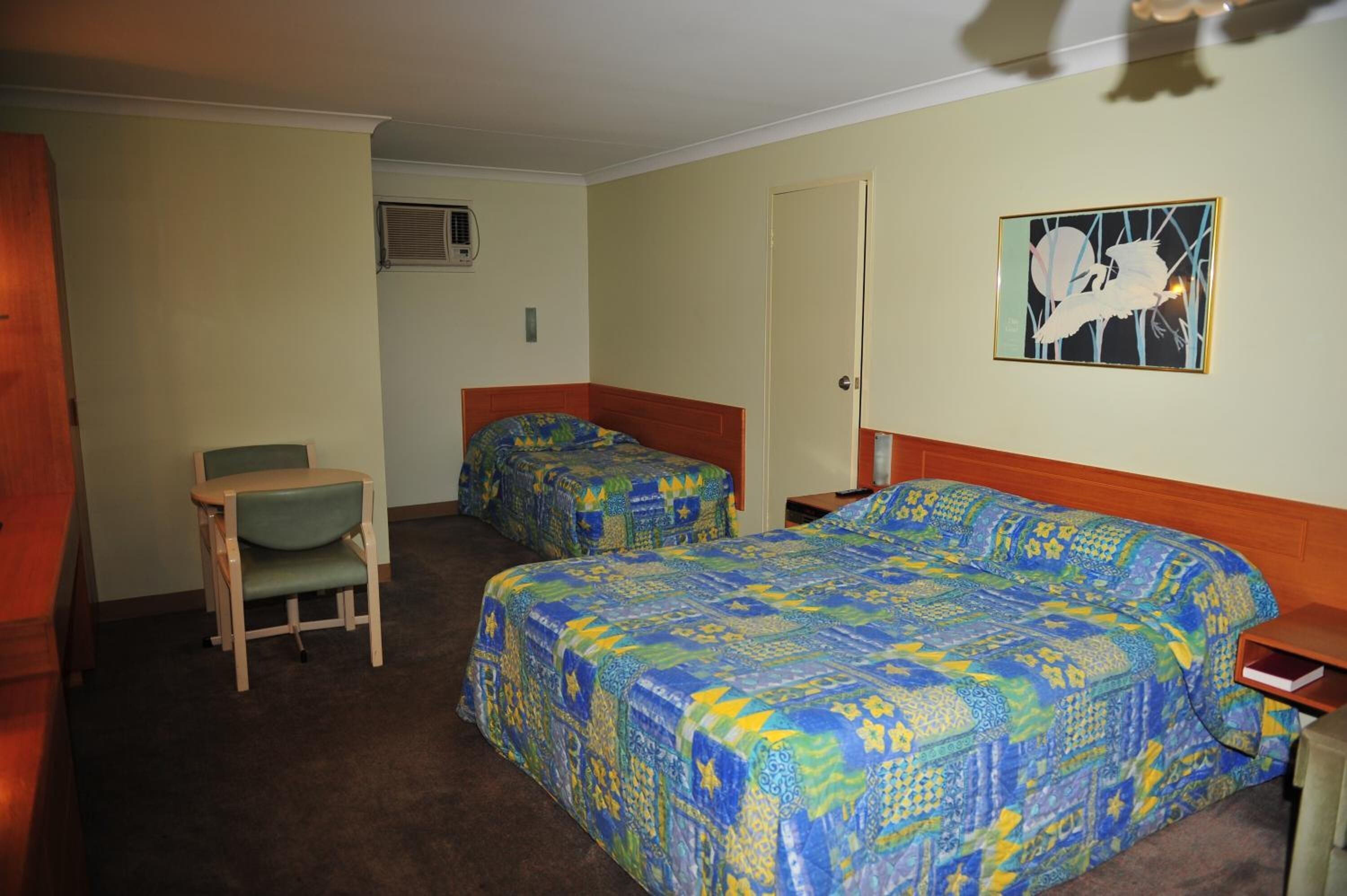 Una habitación con dos camas, una silla y una puerta.