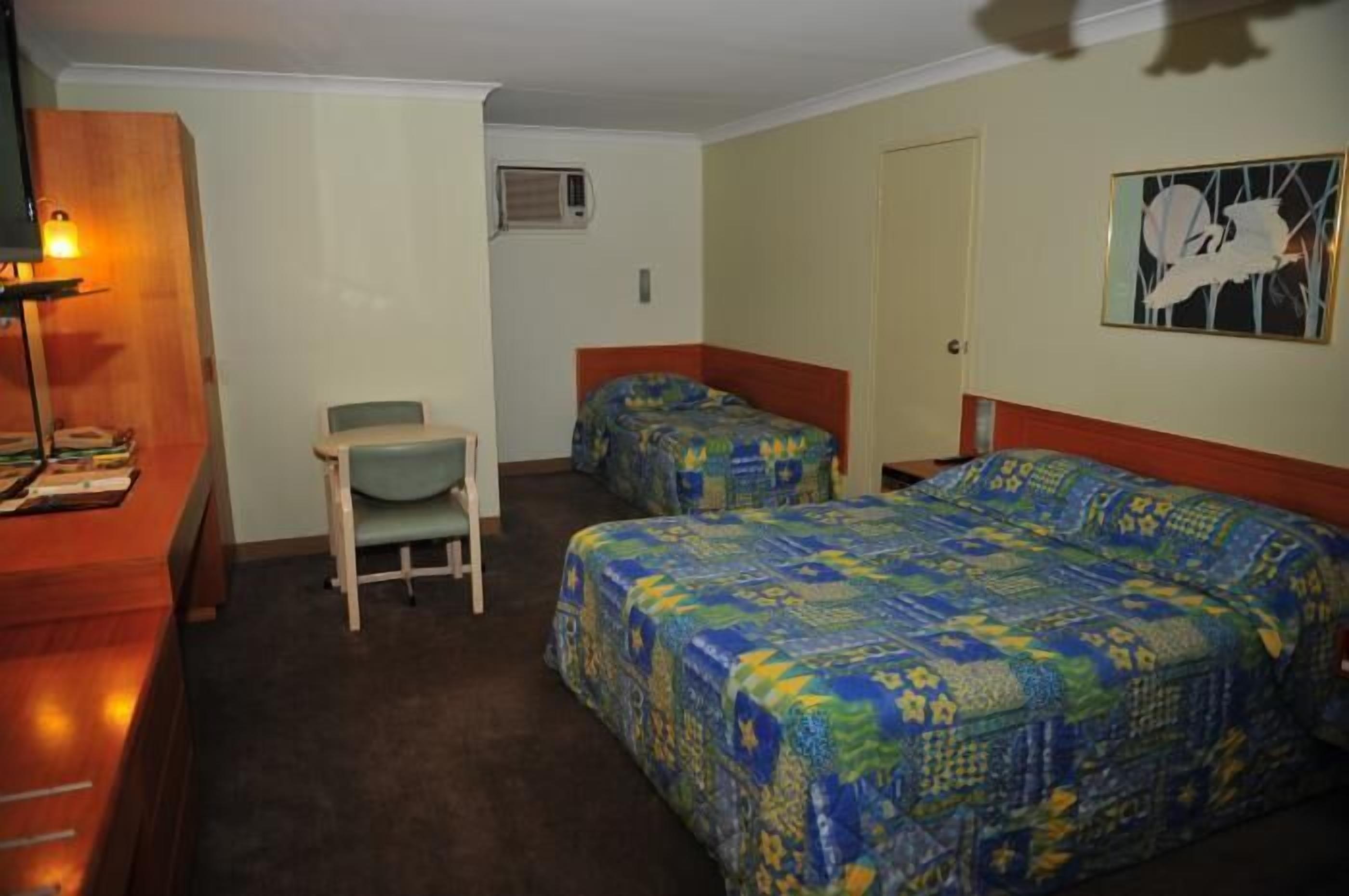 A hotel room with two beds, a desk, and a chair.