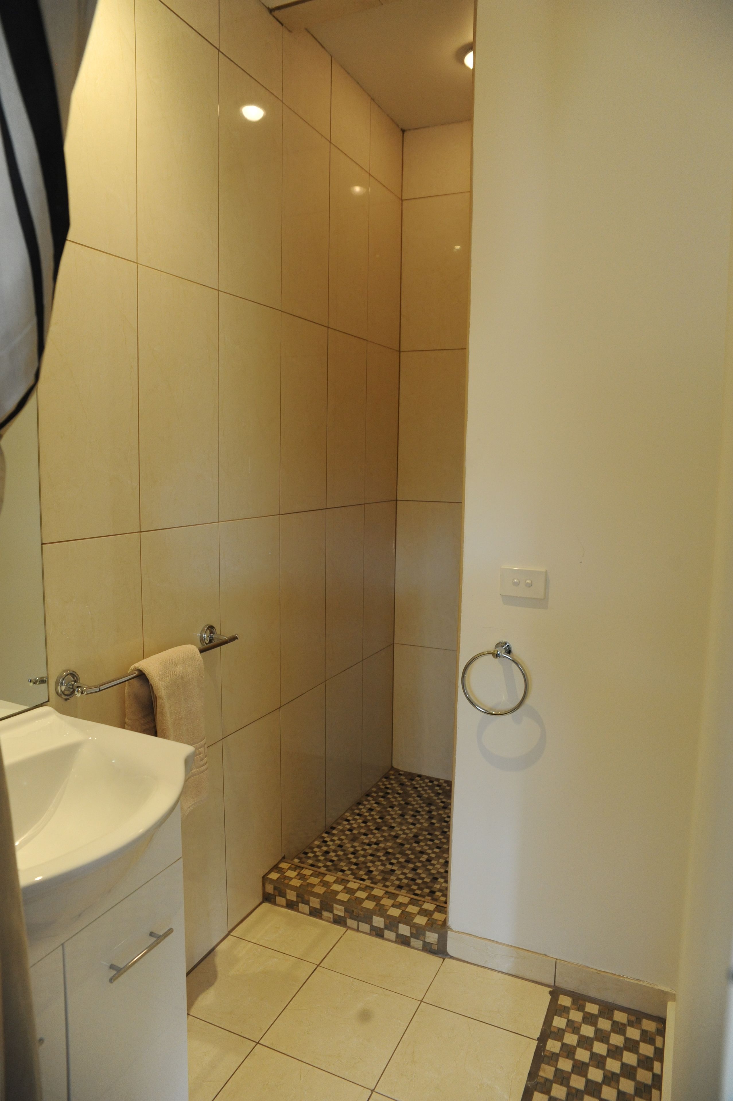 A bathroom with a white sink, a towel rack, a shower with a checkered floor, and a toilet.