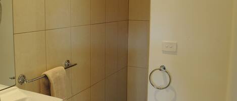 A bathroom with a white sink, a towel rack, a shower with a checkered floor, and a toilet.