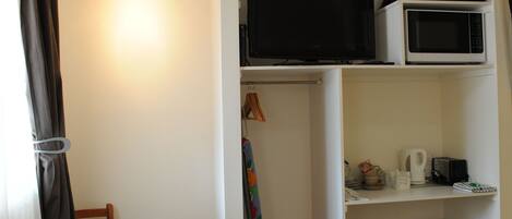 Una habitación compacta con una mesa de comedor, una silla, televisor, microondas y refrigerador.