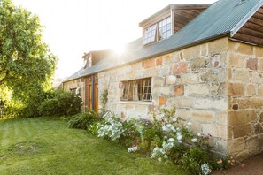 A stone building with a sloped roof and a small porch. - Daisy Bank Cottages (Richmond)