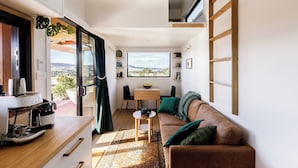 A compact living space with a kitchenette, a dining area, and a sofa with a view of the outdoors. - Daisy Bank Cottages (Richmond)