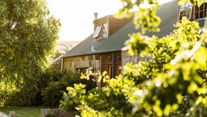 A stone house with a sloped roof, a wooden door, and a window with a shutter. - Daisy Bank Cottages (Richmond)