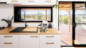 A modern kitchen with a large window, wooden countertop, and white cabinets. - Daisy Bank Cottages (Richmond)
