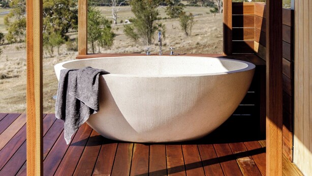 A large freestanding bathtub in an outdoor wooden structure with a view of a rural landscape. - Daisy Bank Cottages (Richmond)