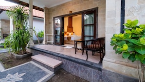 A hotel entrance with a stone facade, a wooden bench, and a potted plant. - Pondok Jenggala (Lembongan Island)