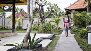 A pathway leading to a building with a tiled roof, surrounded by greenery and a stone wall. - Pondok Jenggala (Lembongan Island)