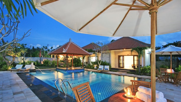 A swimming pool with lounge chairs and umbrellas, surrounded by wooden deck and greenery. - Pondok Jenggala (Lembongan Island)