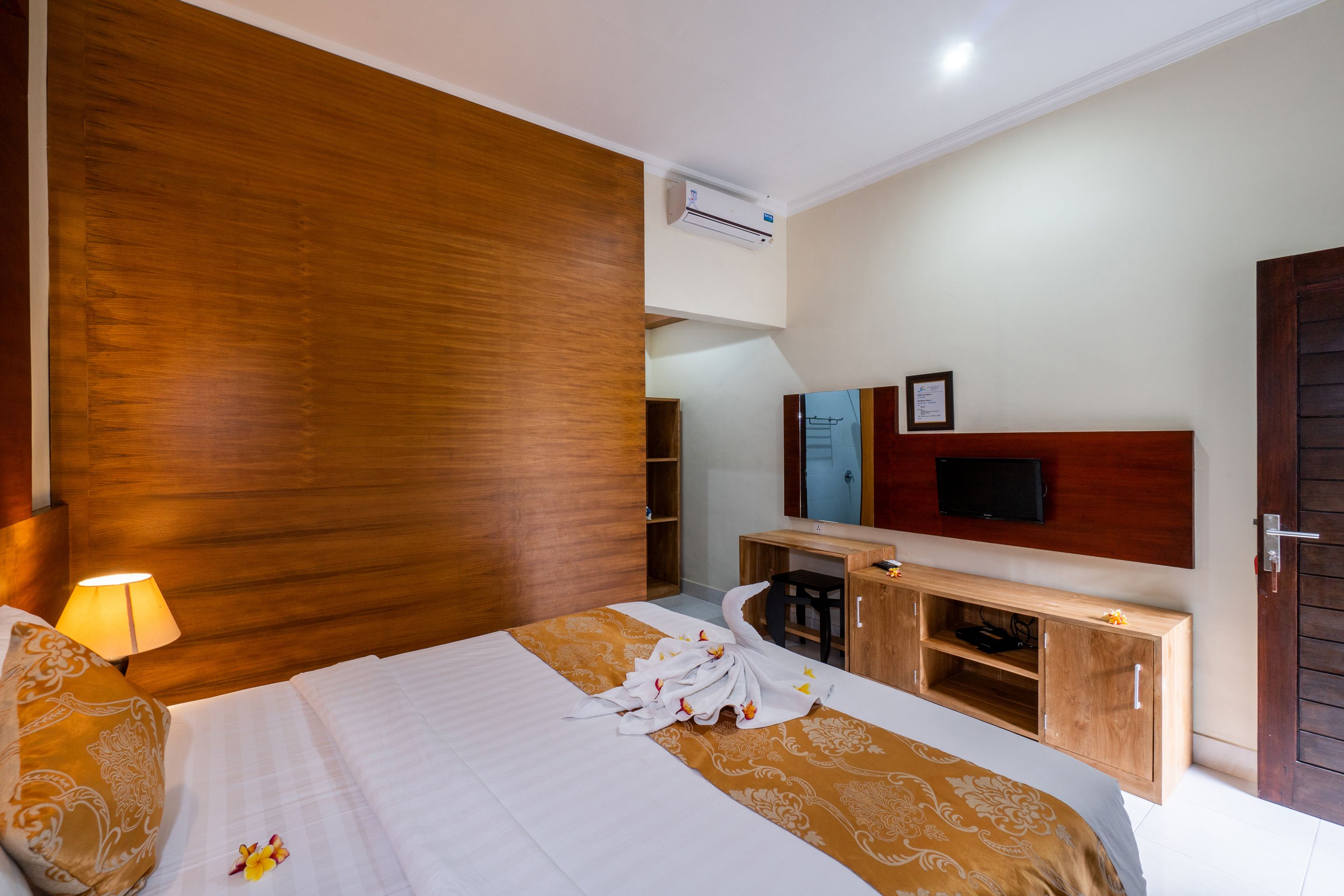 Habitación de hotel con cama, escritorio, televisor y pared de madera.