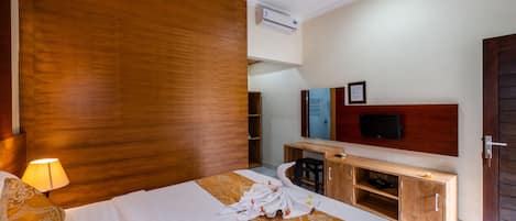 Habitación de hotel con cama, escritorio, televisor y pared de madera.