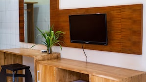 A modern bathroom with a wooden vanity, a large mirror, and a flat-screen TV mounted on the wall. - Pondok Jenggala (Lembongan Island)