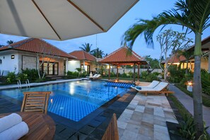 Una piscina al aire libre, sillones reclinables de piscina