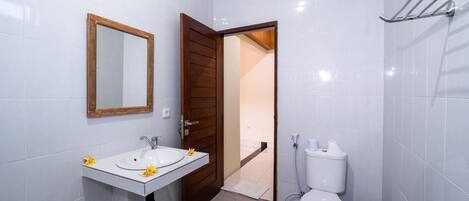 A bathroom with a white sink, mirror, and toilet.